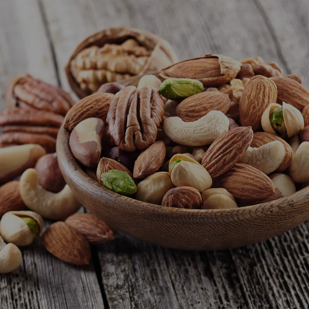 Premium nut packaging solutions—mixed nuts including almonds, cashews, pistachios, and pecans in a rustic wooden bowl